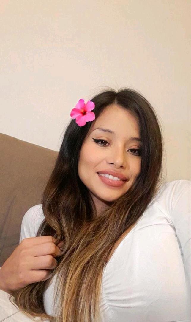 A woman with a flower in her hair smiling at the camera
