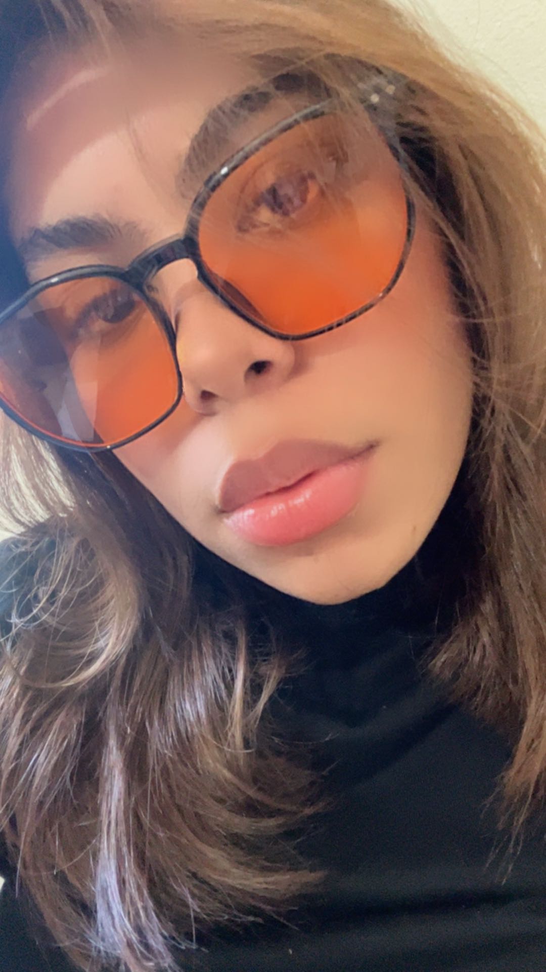 A woman in tinted glasses taking a close selfie