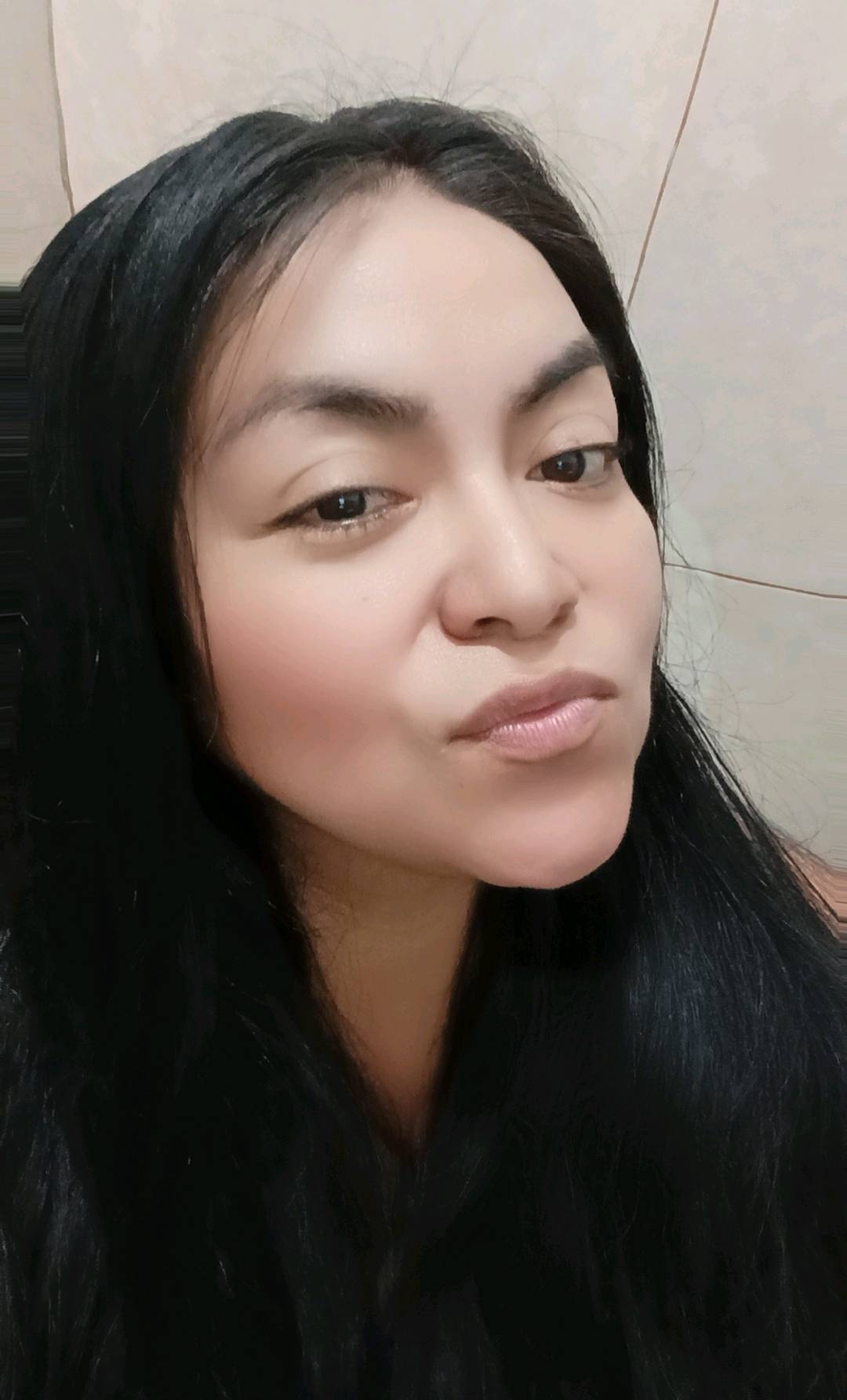 A woman with dark hair resting her chin on her hand