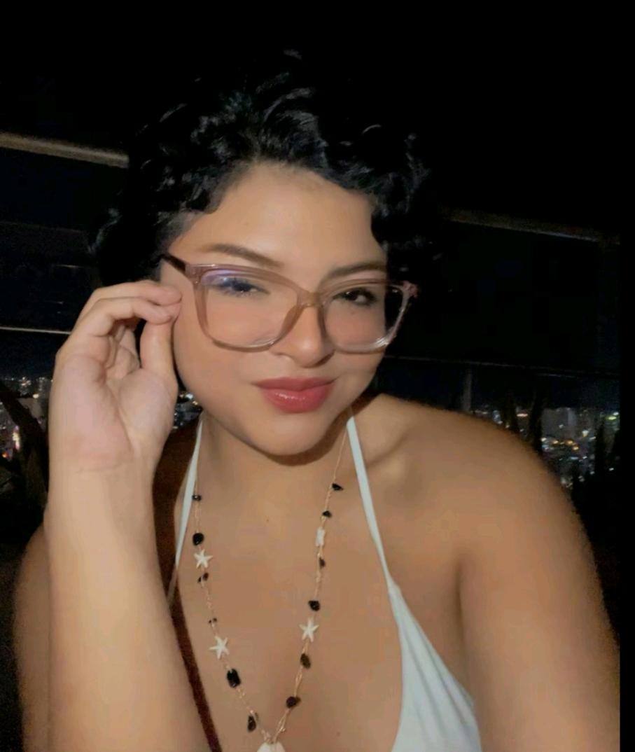 A woman with curly hair adjusting her glasses at night, talking in a random voice chat