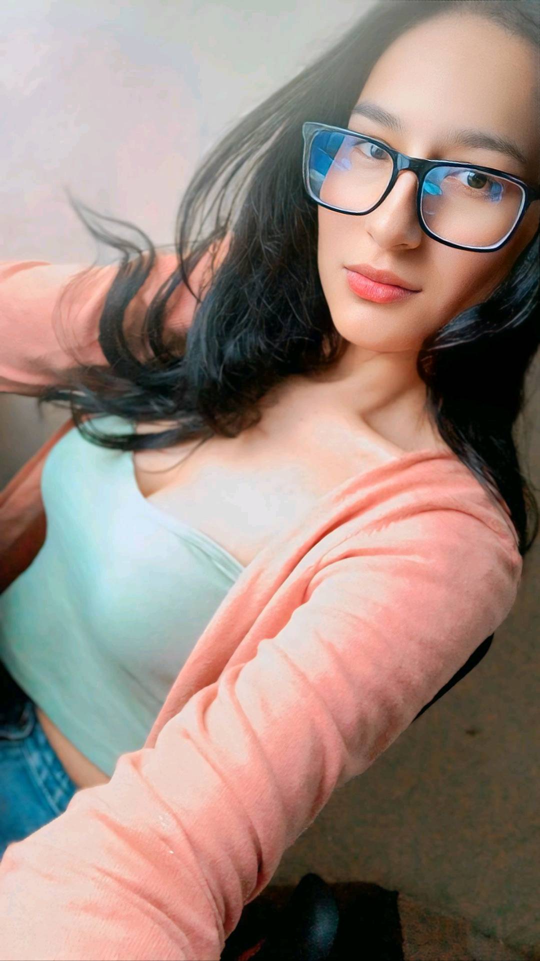A woman in glasses smiling at her phone, typing in a random text chat