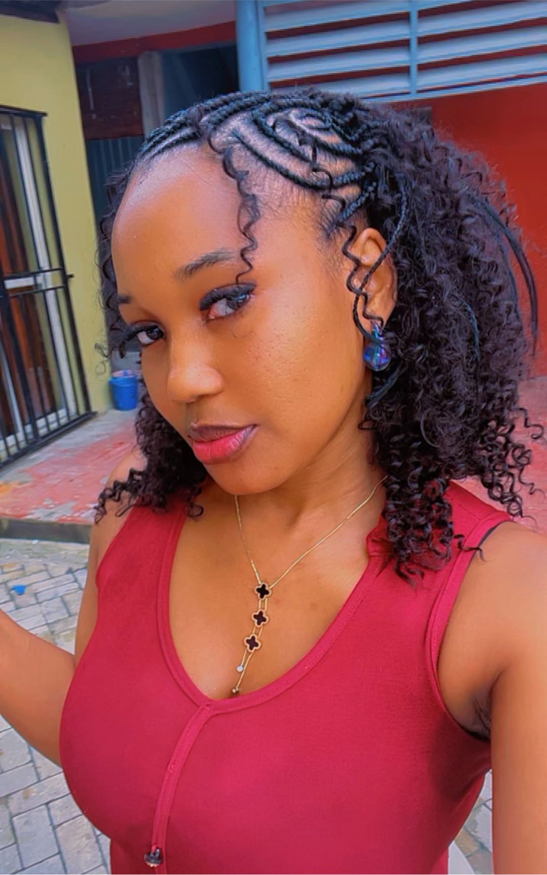 A woman with curly hair in a red top by a doorway