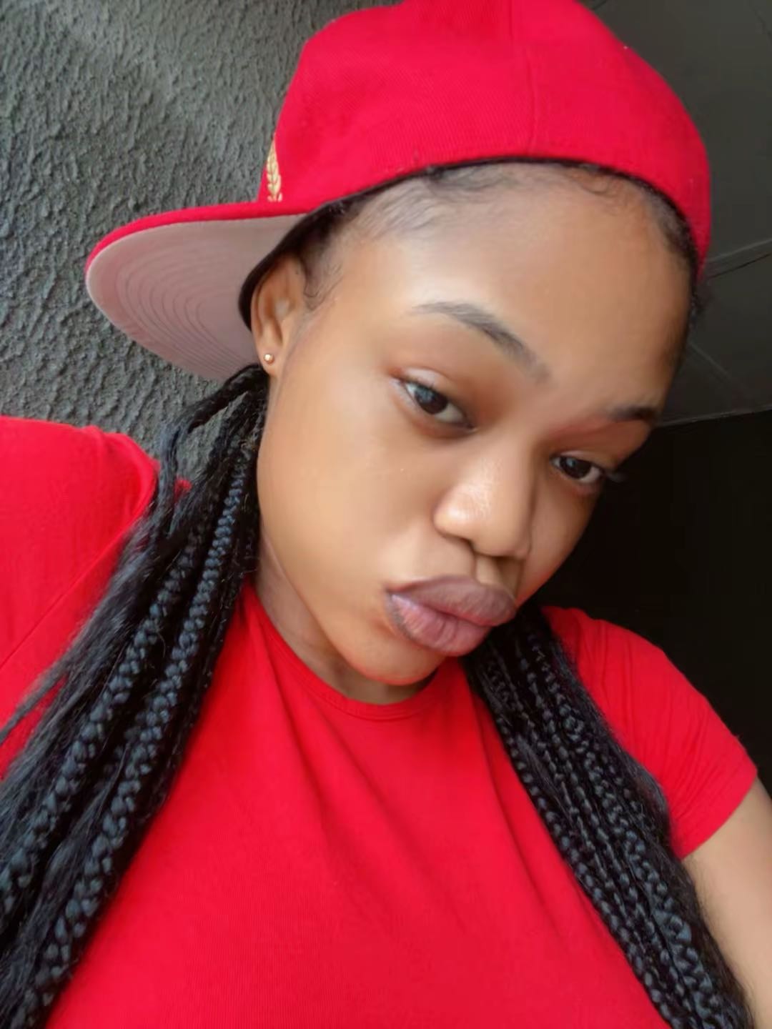A woman in a red cap and braids taking a selfie, someone new to talk to